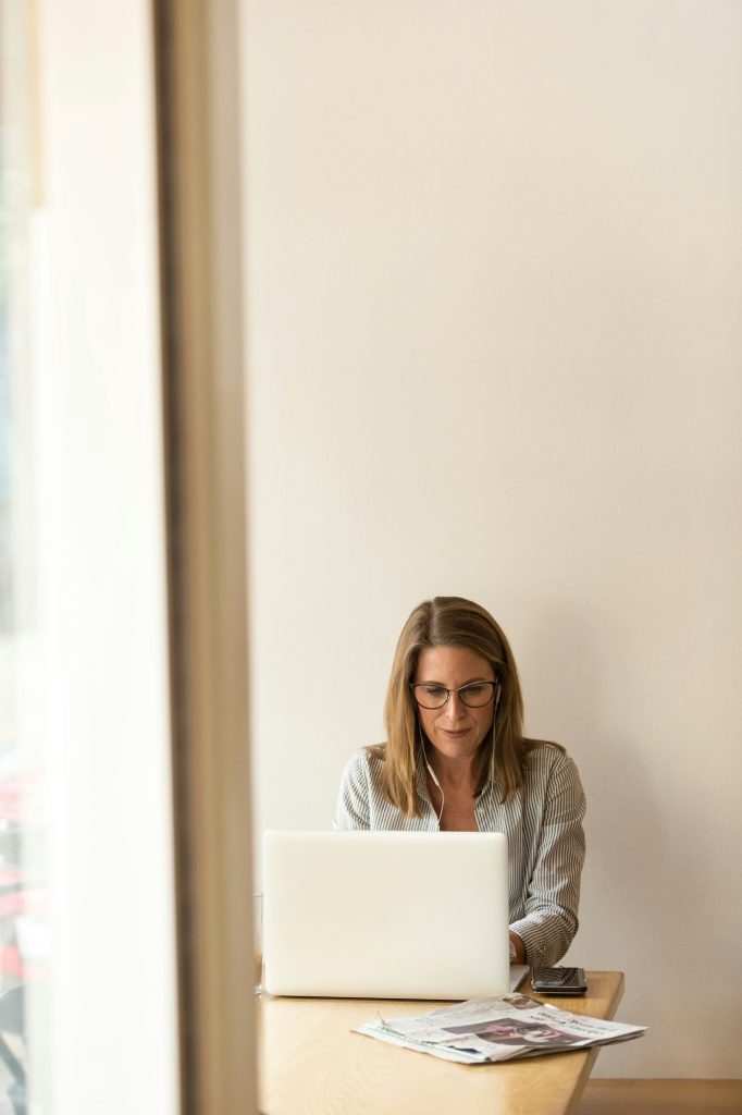 eine Frau mit Brille und Kopfhörer sitzt vor ihrem Laptop.